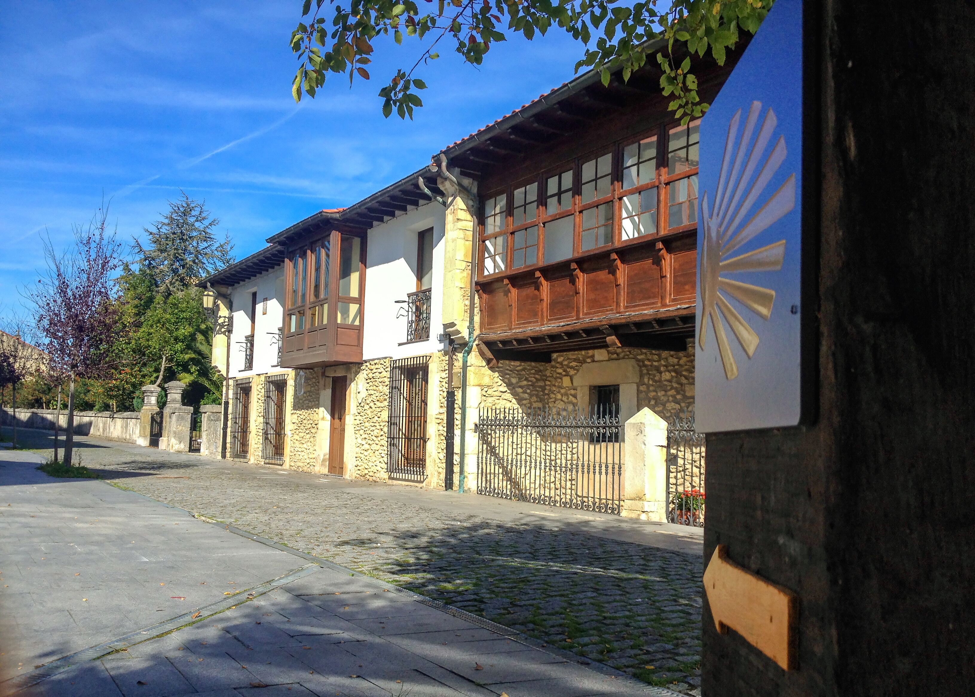 Street of Unquera town with Camino de Santiago sign with scallop and yellow arrow