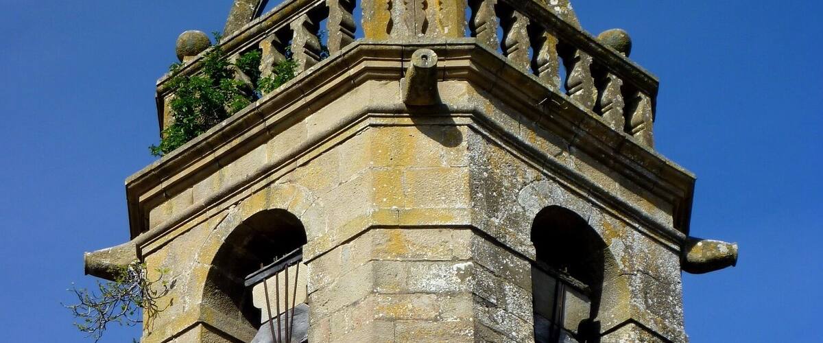 A stone bell tower with a weather vane on top.