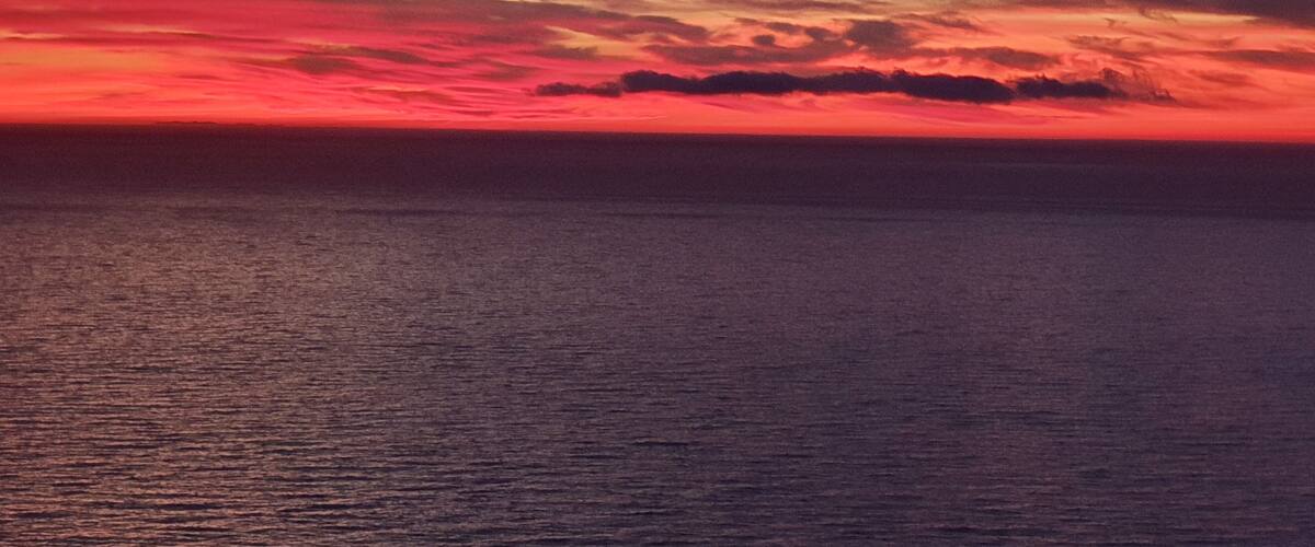A sunset over a calm sea with a vibrant sky.