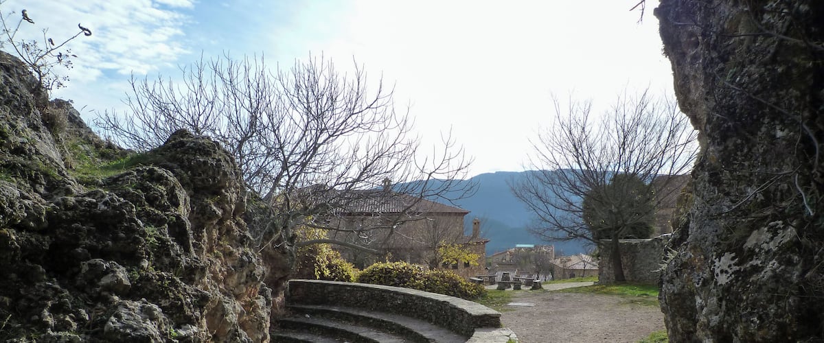 A stone amphitheater with a dirt path leading through a rocky landscape.