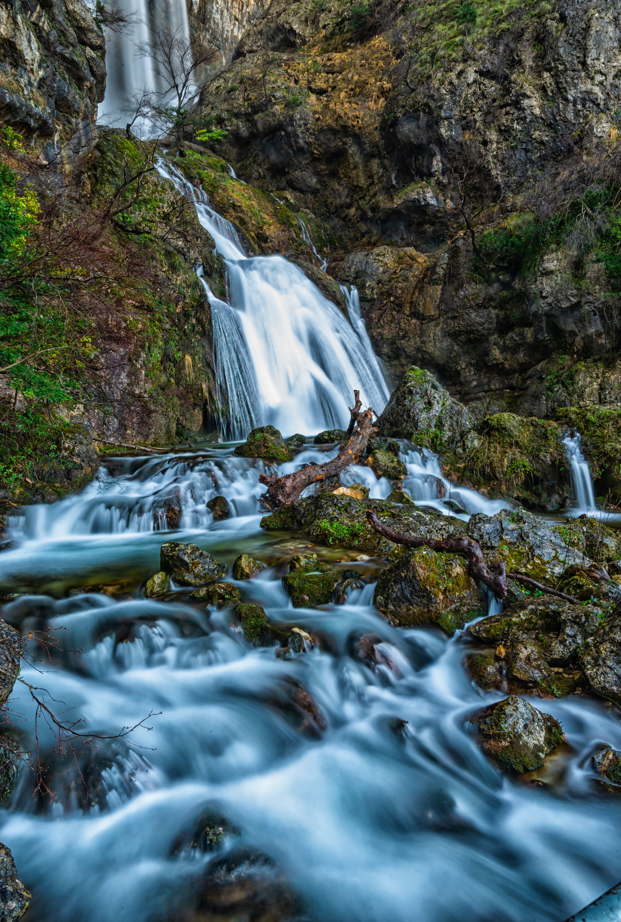 A waterfall cascading over rocks in a forested area.