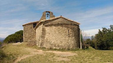 A stone church with a bell tower and a weather vane on a hill.