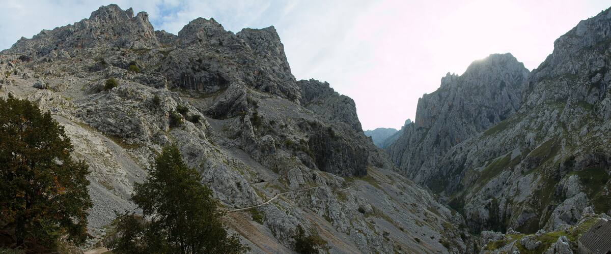 A rugged mountain landscape with steep rocky cliffs and sparse vegetation.