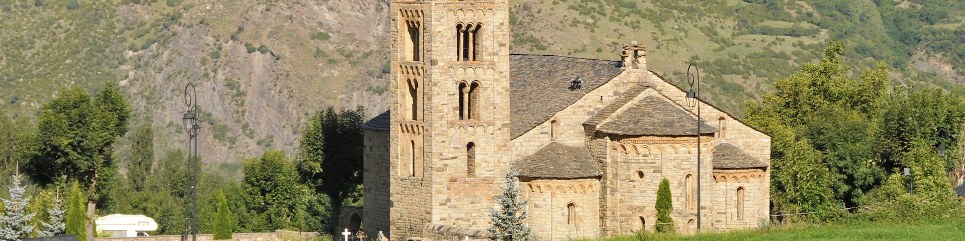 A church with a tall bell tower and a mountain backdrop.