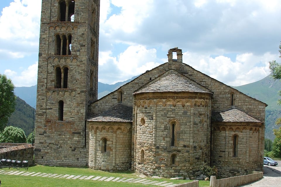 A stone church with a tall bell tower and a smaller building with arched windows.