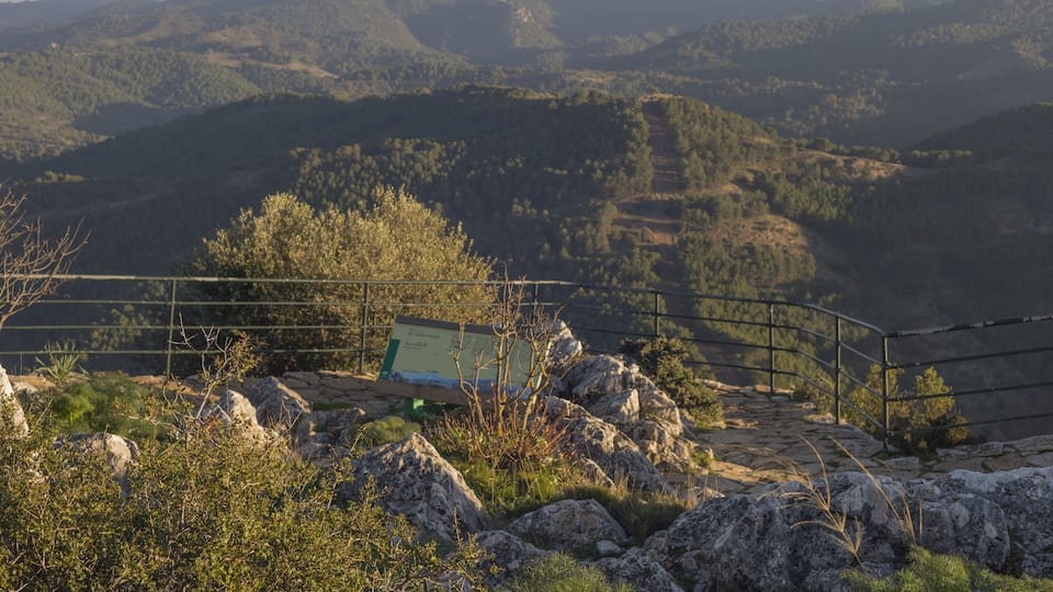 A mountainous landscape with a metal railing and a sign.