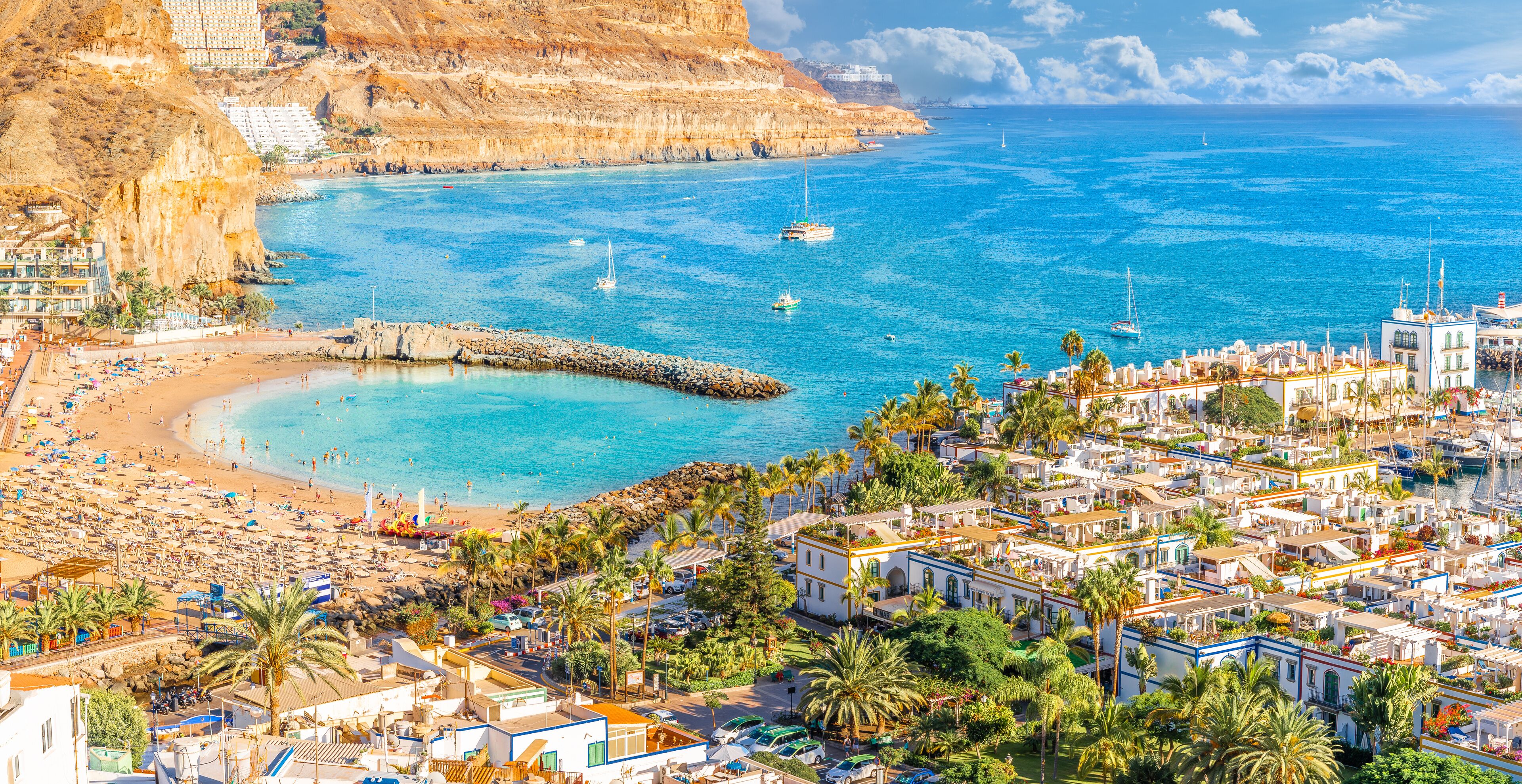 A coastal town with a beach, boats, and buildings.