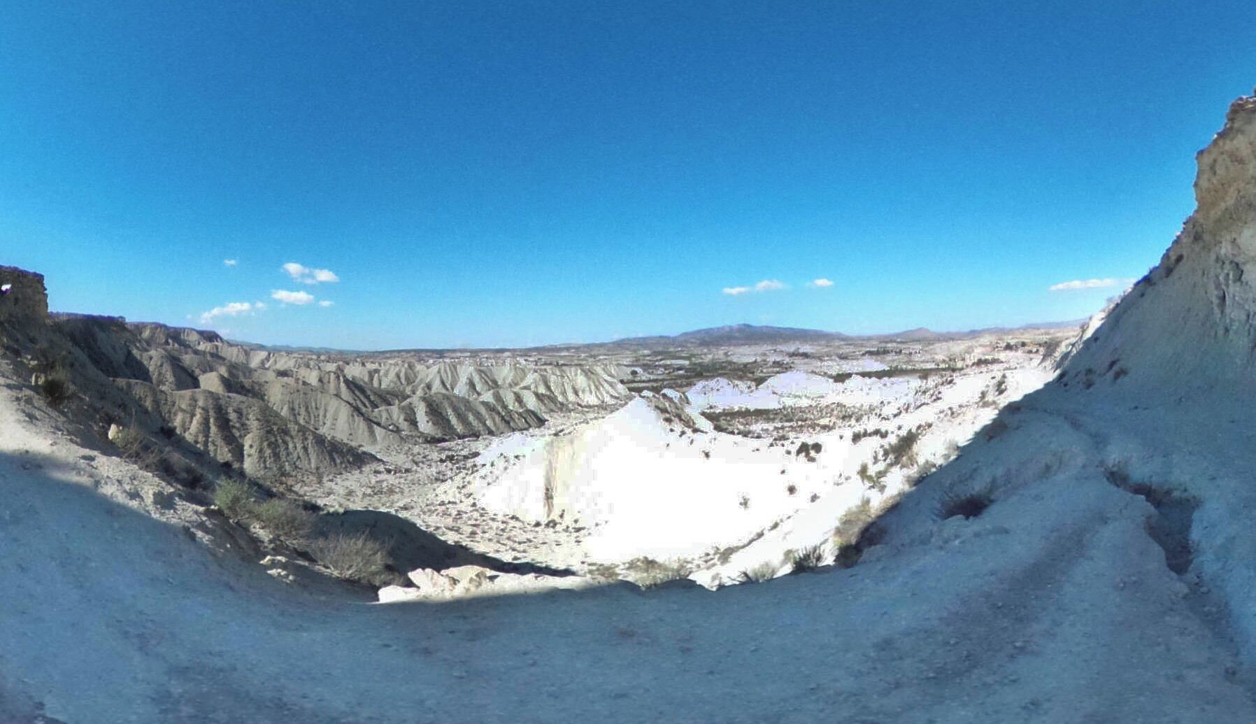 A barren landscape with steep, eroded cliffs and a vast, open valley.