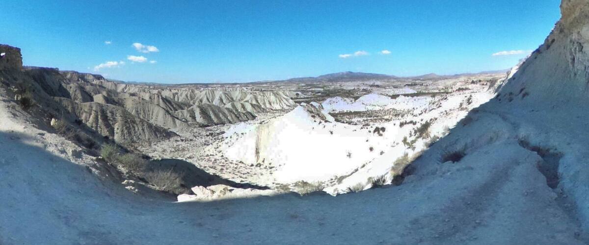 A barren landscape with steep, eroded cliffs and a vast, open valley.