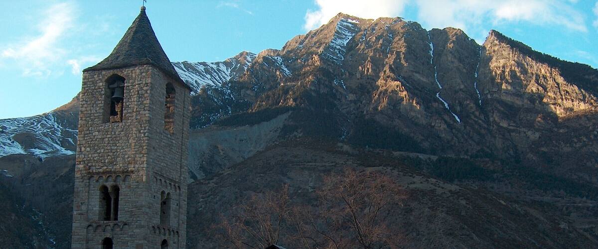 A stone church with a bell tower and a mountain backdrop.