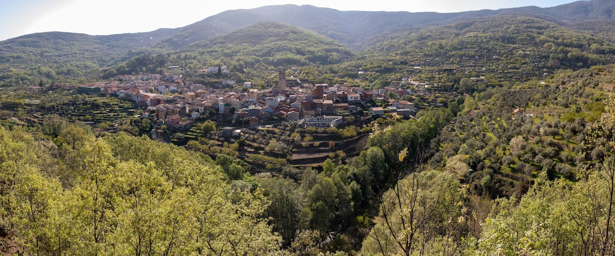 A mountainous village with terraced fields and a prominent church.