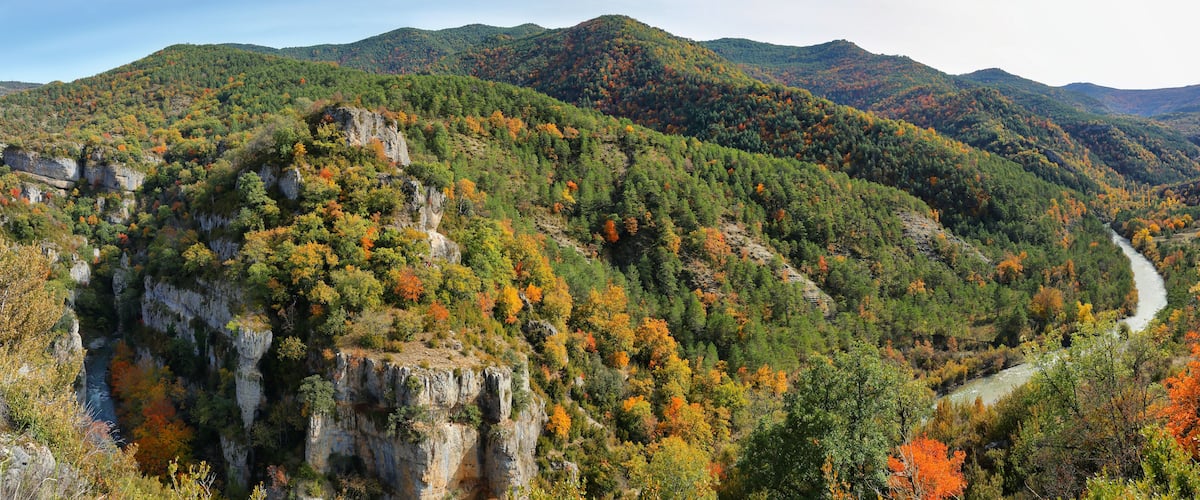 A river winding through a mountainous valley with autumn foliage.
