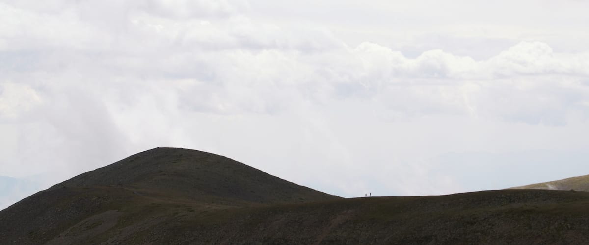 A mountainous landscape with two prominent hills under a cloudy sky.