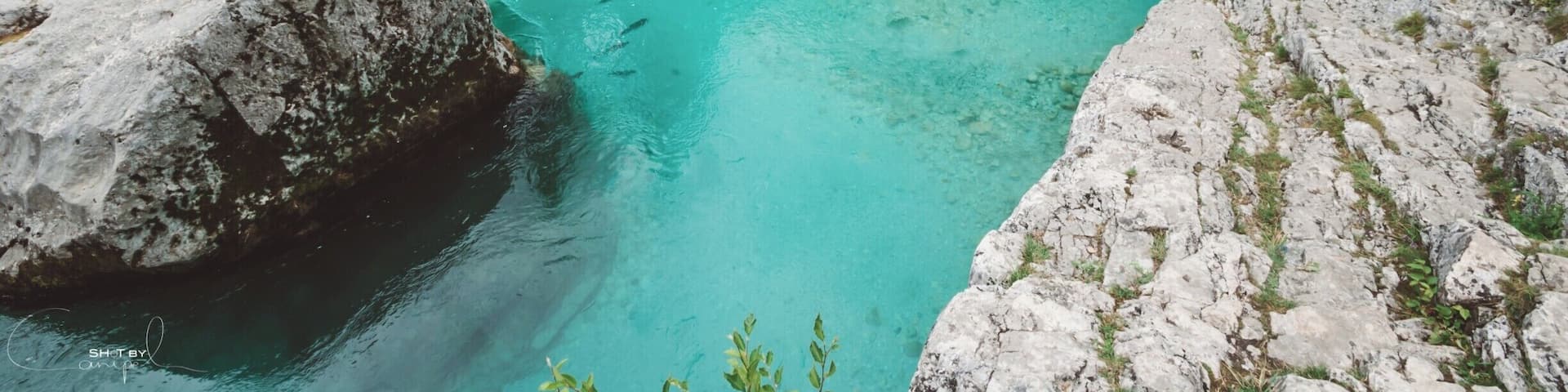 A turquoise river flowing through rocky terrain with large boulders and dense greenery.