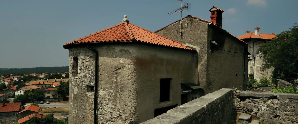 A historic stone tower with a red-tiled roof, part of an old fortification.