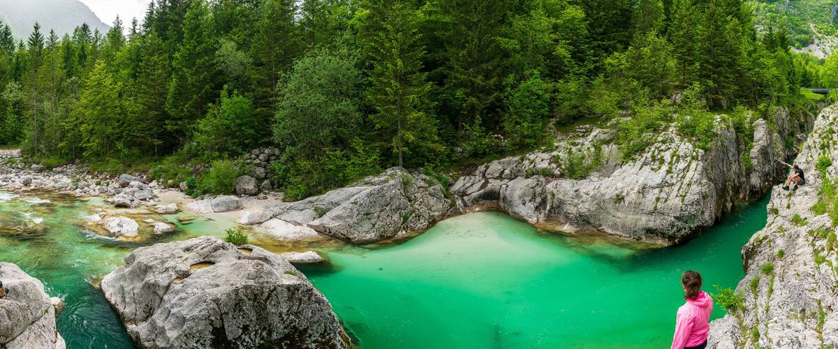 Een turquoise rivier die door een rotsachtige kloof stroomt, omringd door dicht bos.