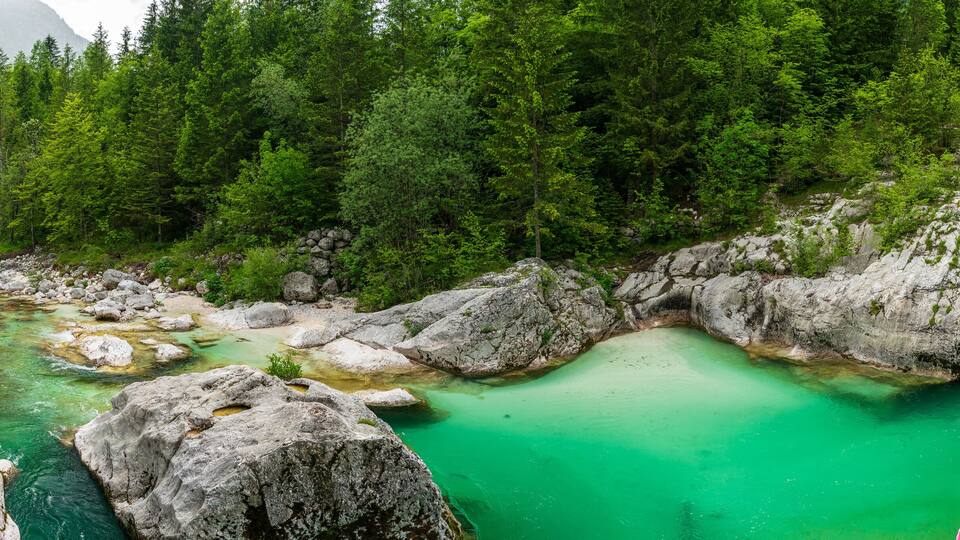 A turquoise river flowing through a rocky gorge surrounded by dense forest.