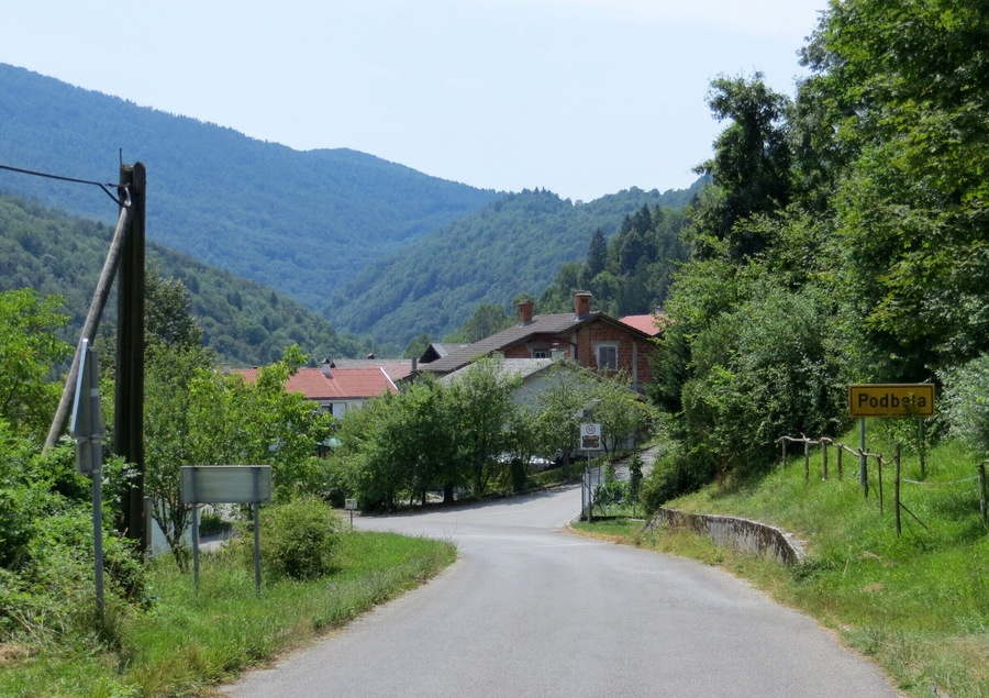 A rural road in Podbresta, surrounded by greenery and houses.