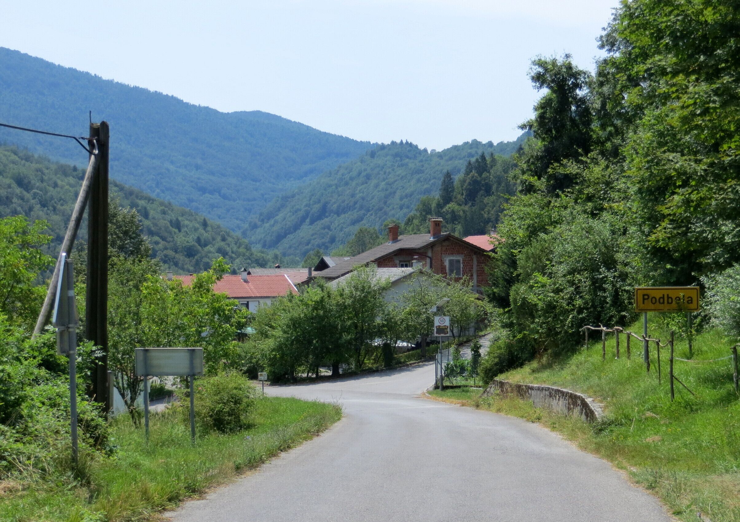 A rural road in Podbresta, surrounded by greenery and houses.