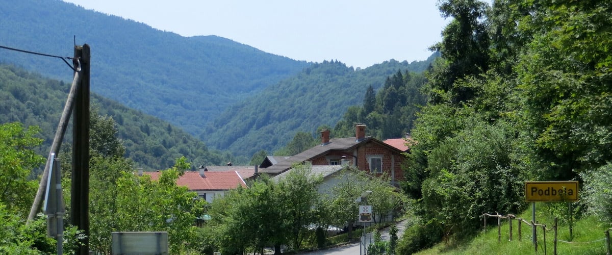 A rural road in Podbresta, surrounded by greenery and houses.