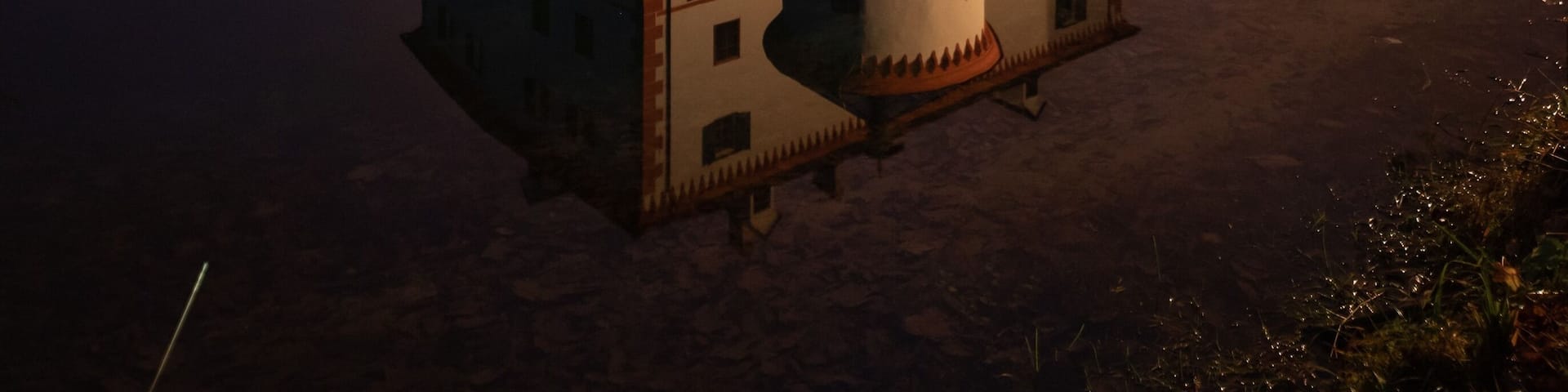 A castle with a moat and a bridge, reflecting in the water.