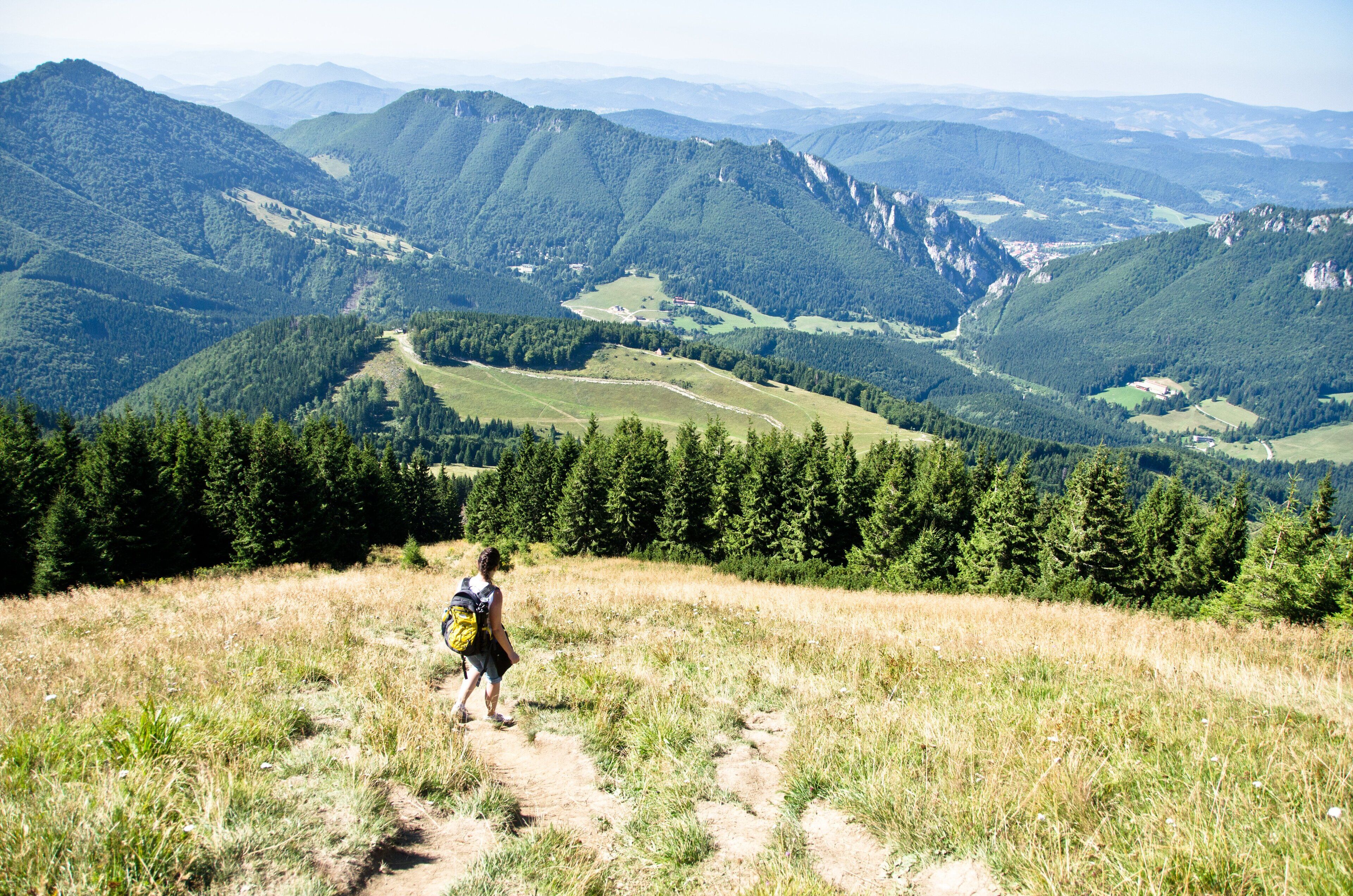 A hiker on a trail with a mountainous landscape in the background.