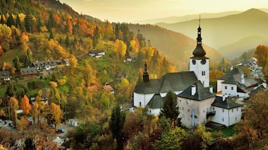 Fall in Slovakia. Old mining village. Historic church in Spania dolina. Autumn colored trees at sunset.