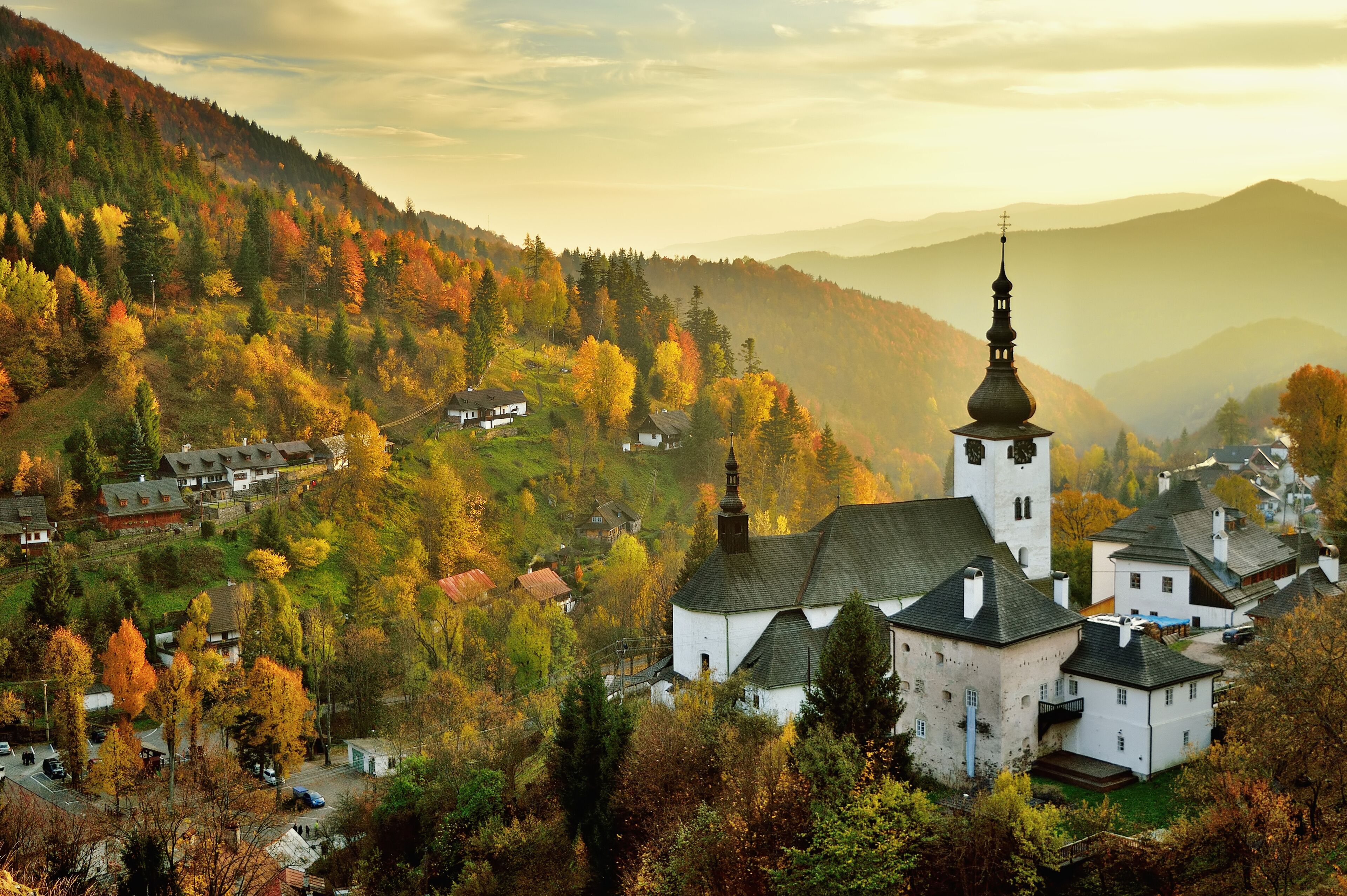 A village with a prominent church and surrounding autumn foliage.