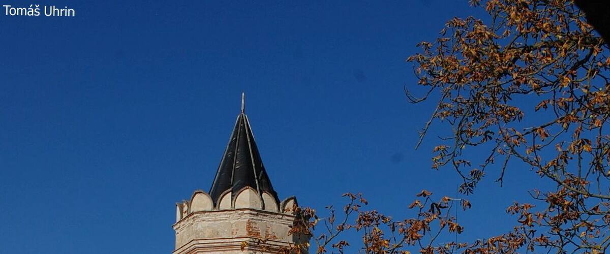 A historic building with a clock tower, surrounded by leafless trees and debris.