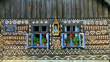 A traditional wooden building with decorative patterns and two windows with flower boxes.
