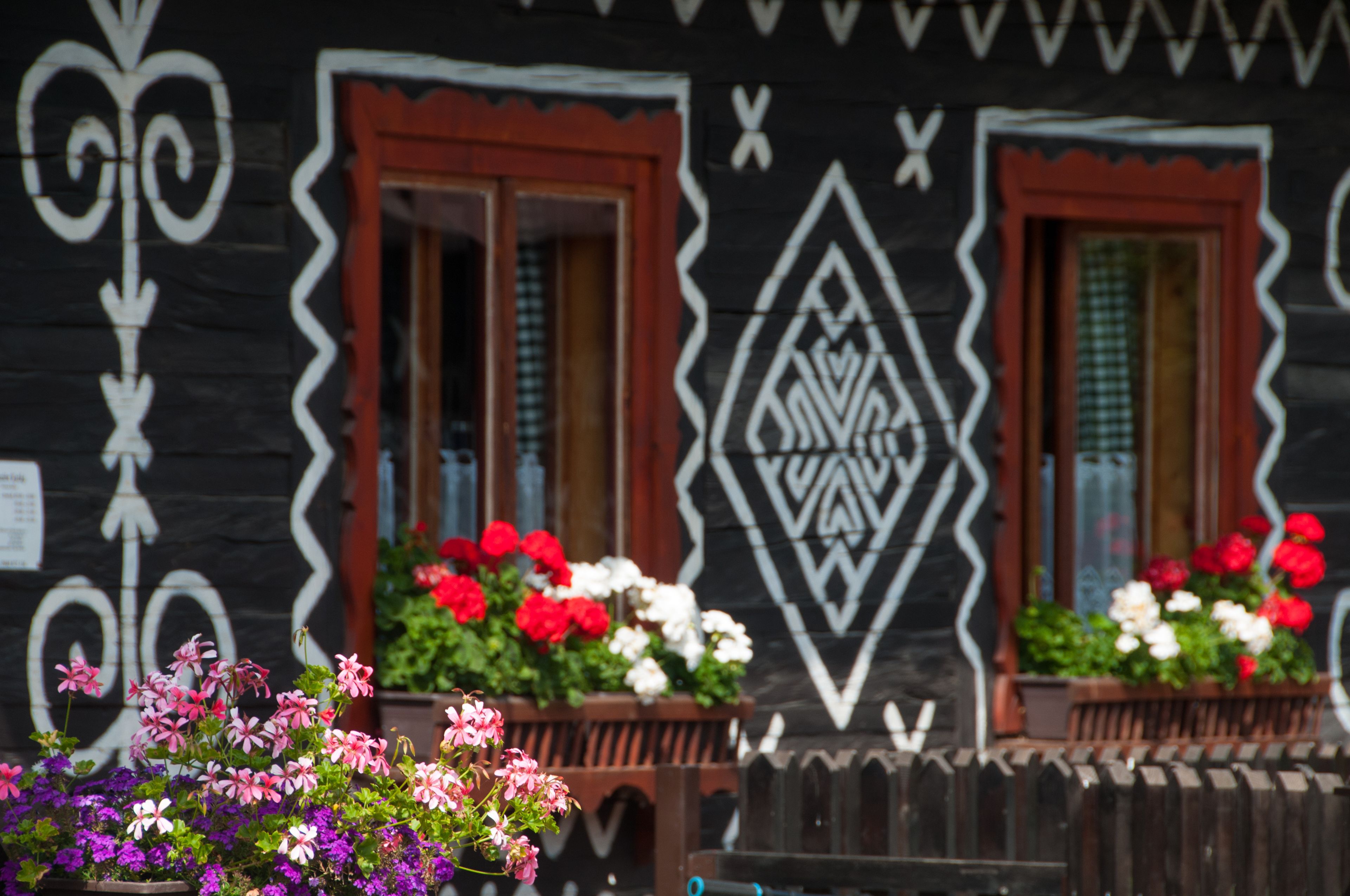 A wooden house with decorative patterns and flower boxes.