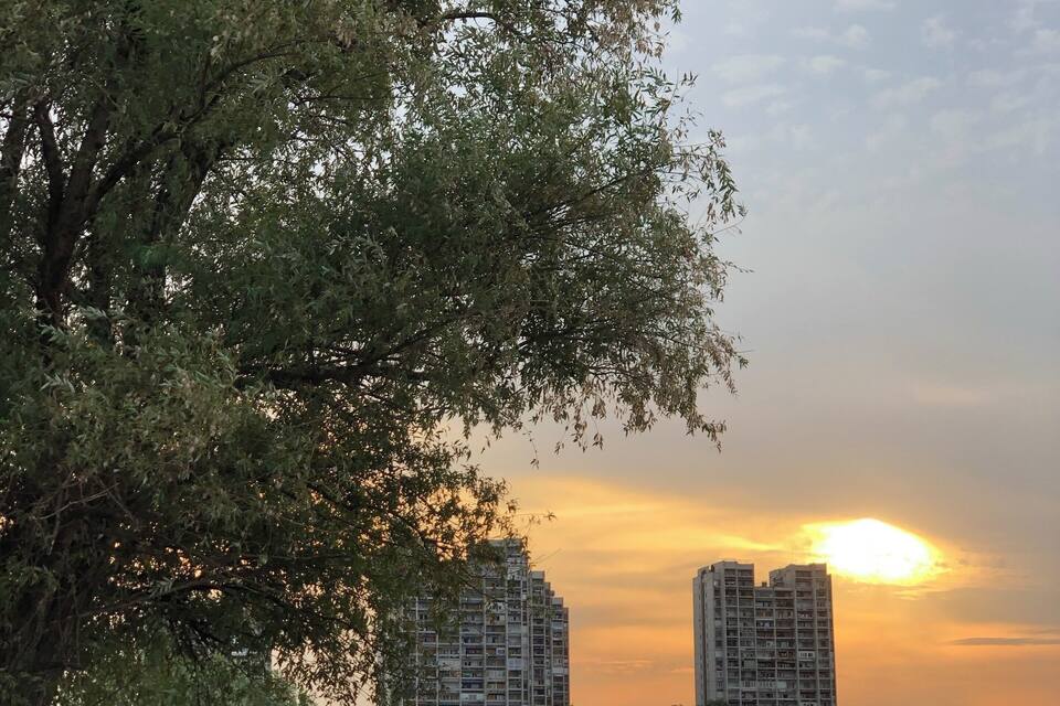 Ein See bei Sonnenuntergang, im Hintergrund Gebäude.