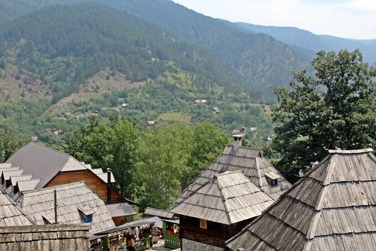 A village with traditional wooden houses and a mountainous backdrop.