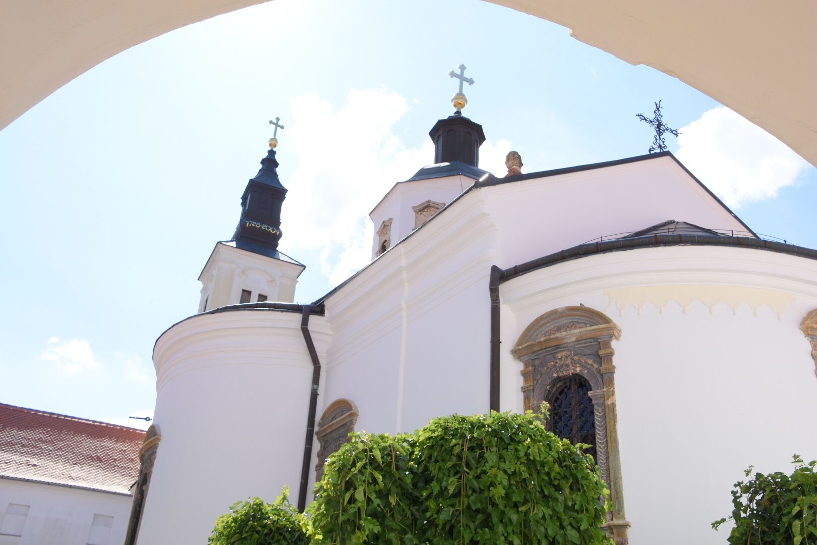 A white church with a cross-topped steeple and a smaller spire.