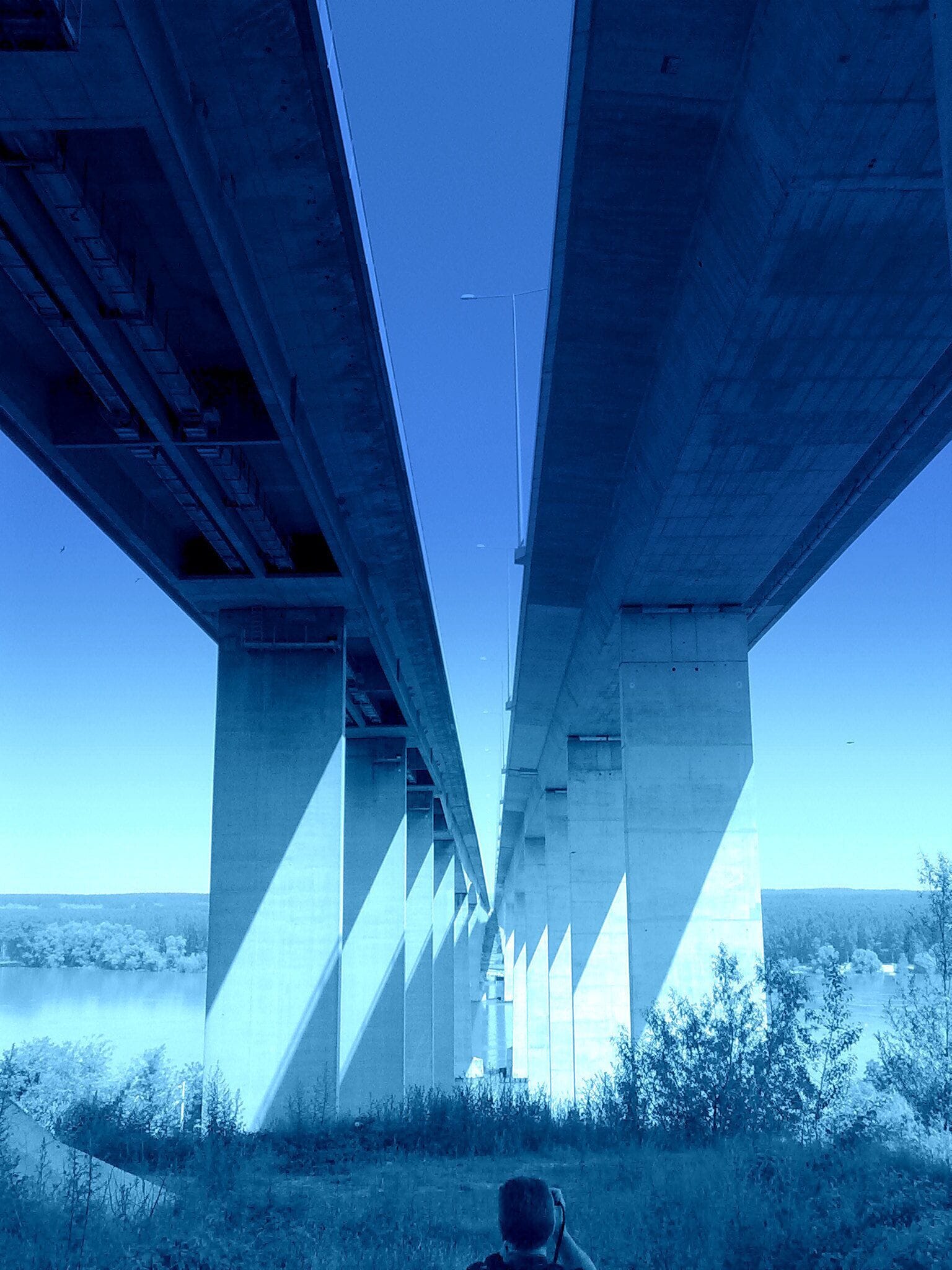 A bridge with concrete pillars and a clear blue sky.