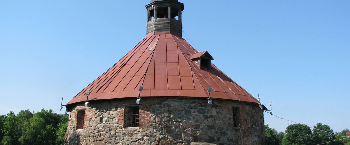 A stone building with a red roof and a tower.