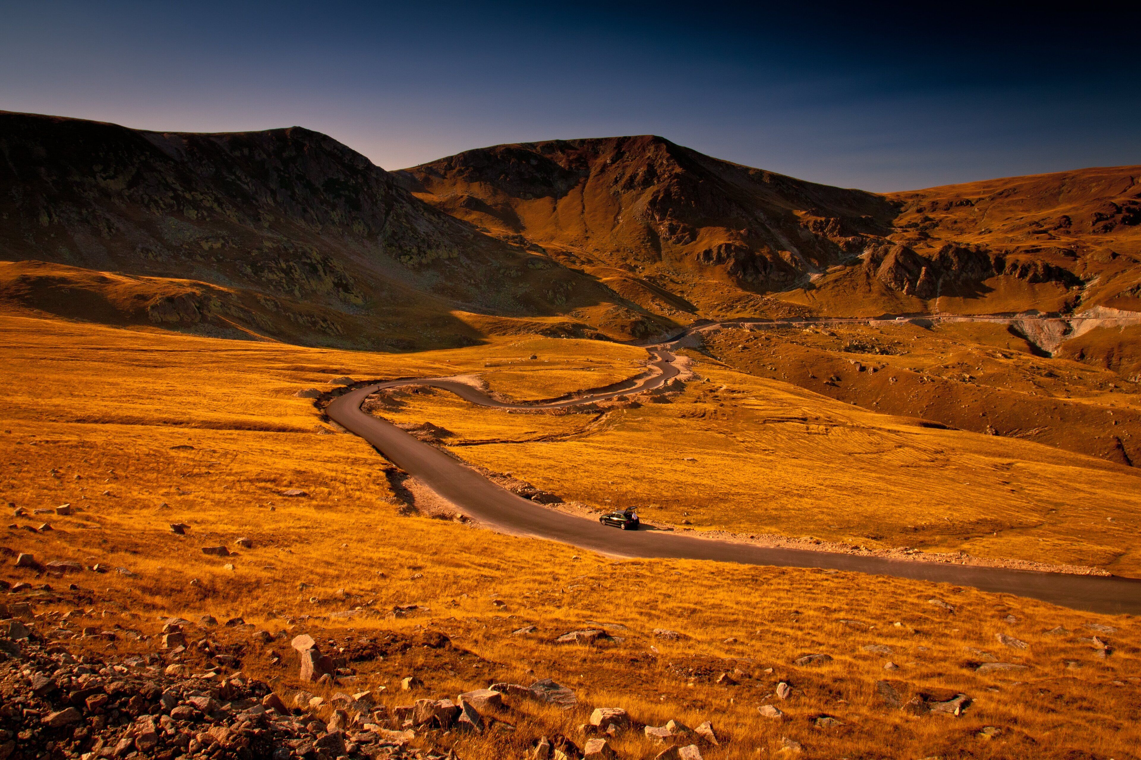 A winding road through a mountainous landscape with rocky terrain and sparse vegetation.