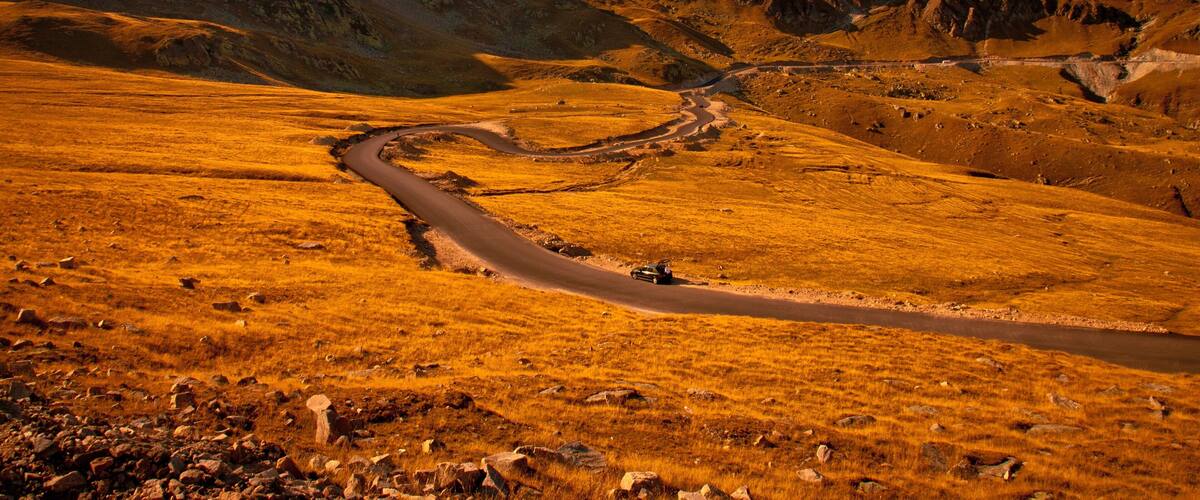 A winding road through a mountainous landscape with rocky terrain and sparse vegetation.