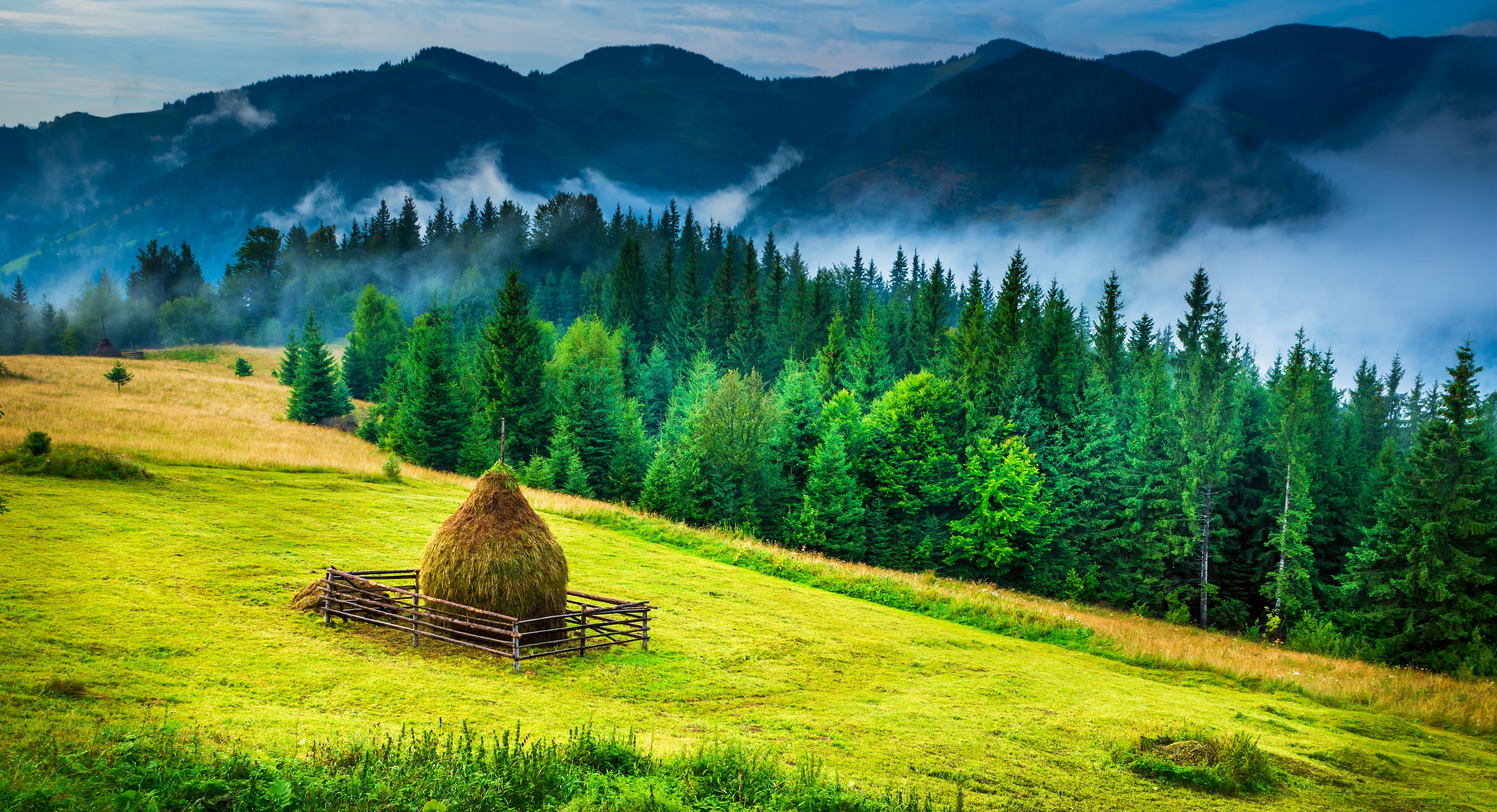 Amazing mountain landscape with fog and a haystack