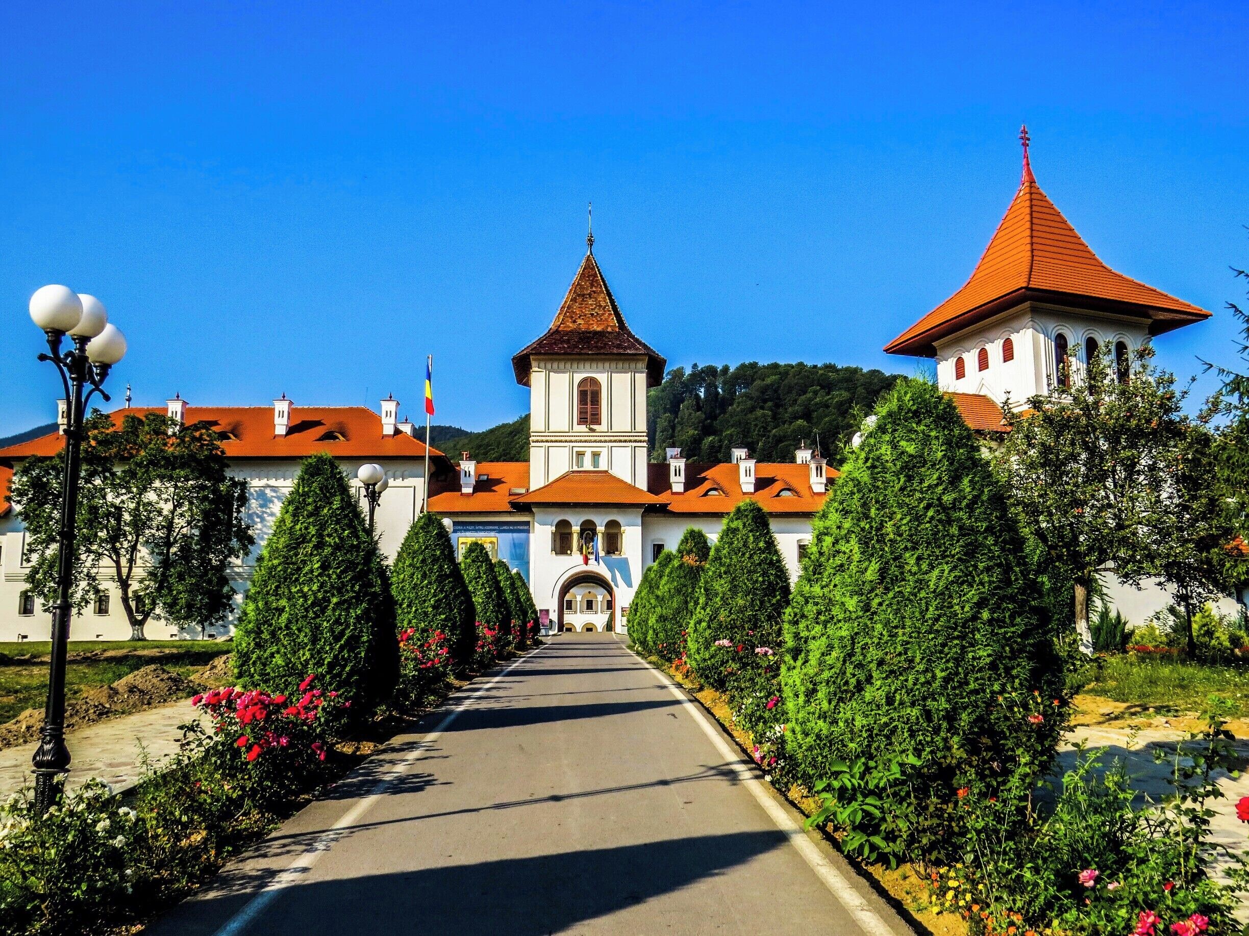 A historic building with a red-tiled roof, a central tower, and a smaller tower to the right.