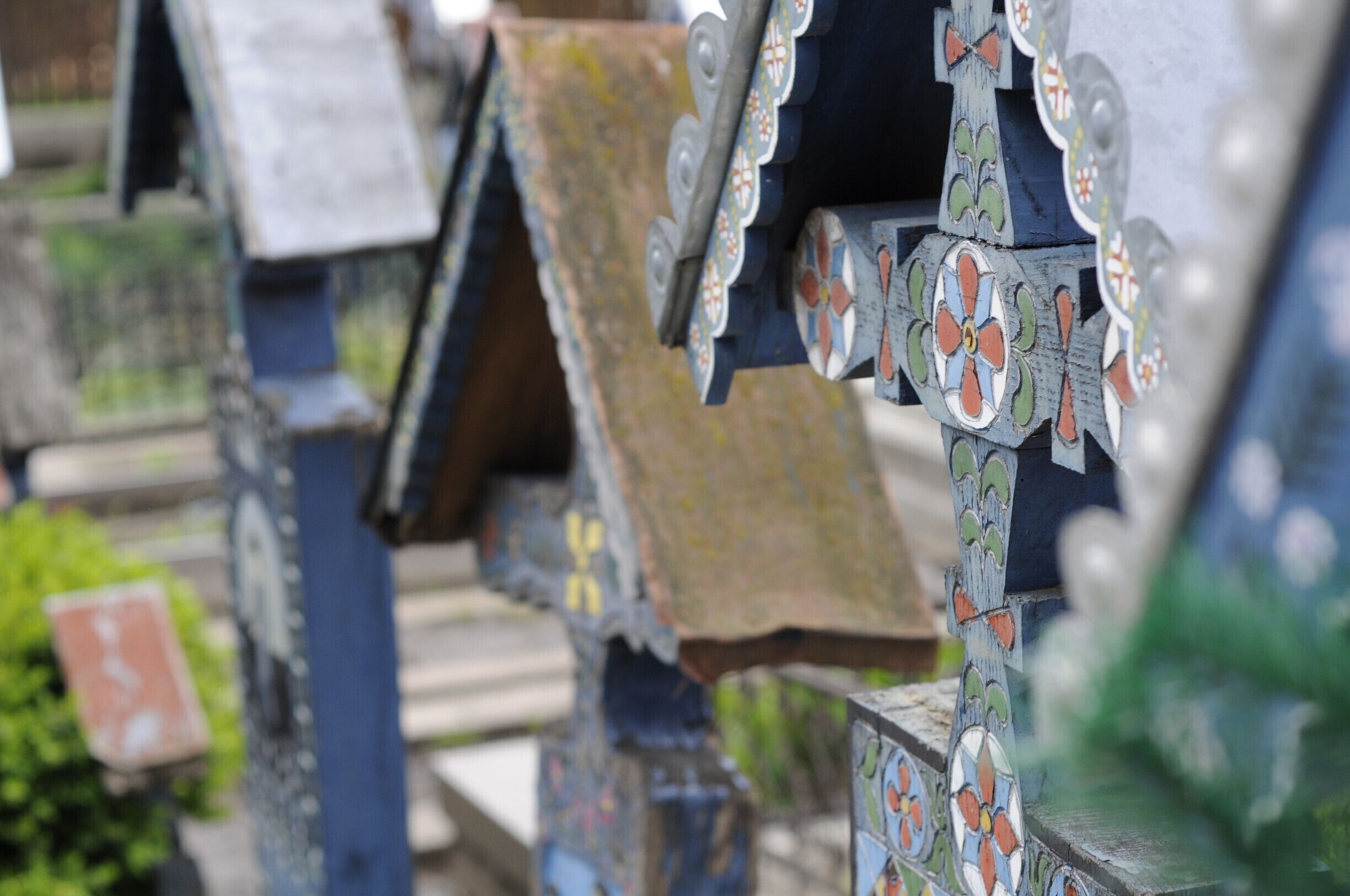 A close-up of a metal fence with colorful, patterned tiles.