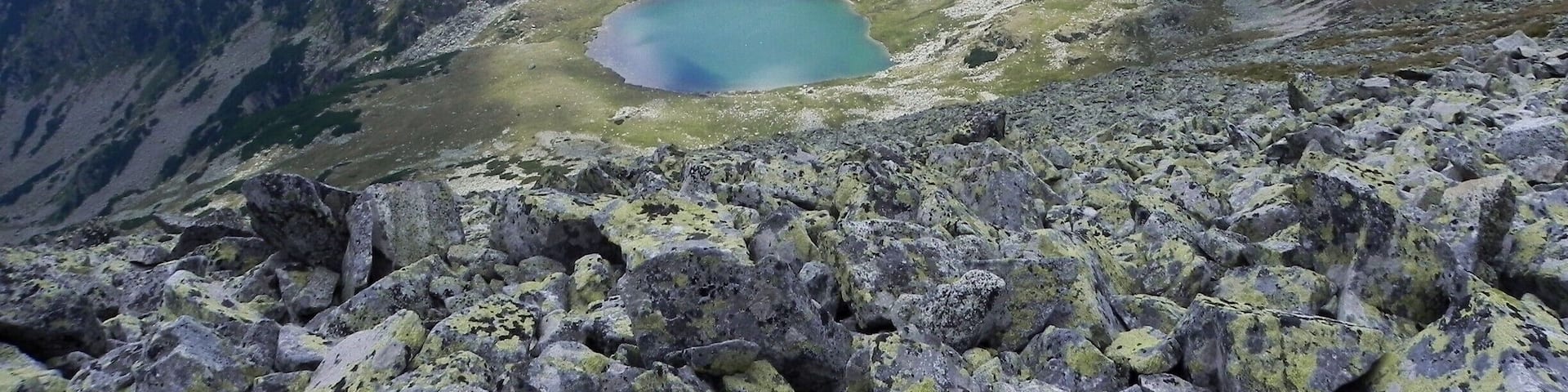 A mountain landscape with a small lake surrounded by rocky terrain.
