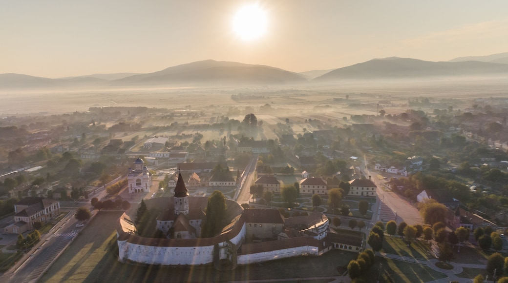 Et panorama over en by med en markant kirke i forgrunden, omgivet af boligområder og marker.