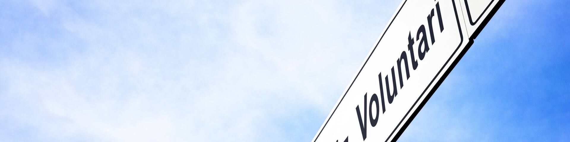 A directional sign with the word 'Volontari' and an arrow pointing left.