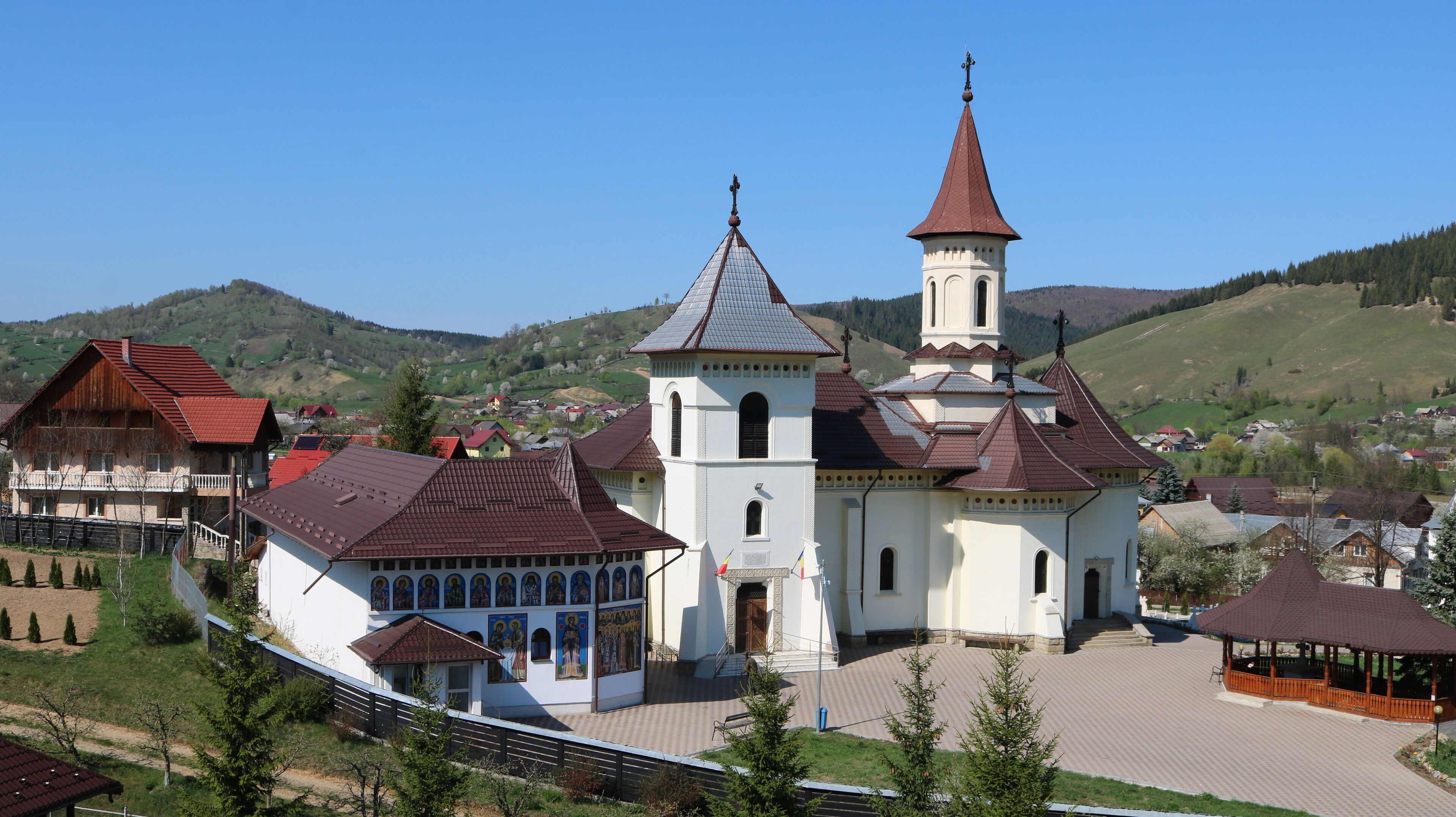 A church with a tall steeple, surrounded by houses and a park.