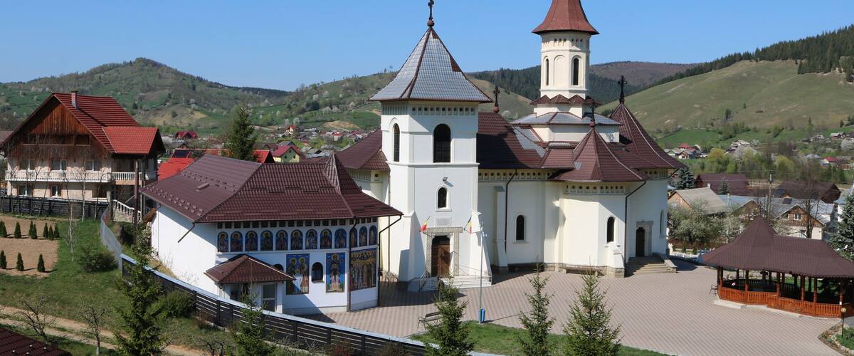 A church with a tall steeple, surrounded by houses and a park.