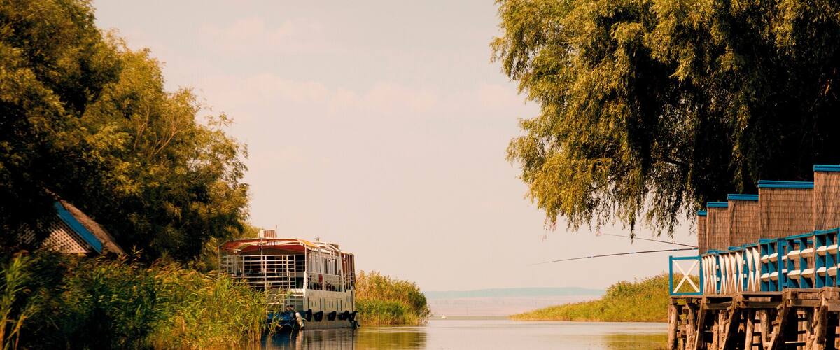 A river with a boat docked on the left and a wooden pier on the right.