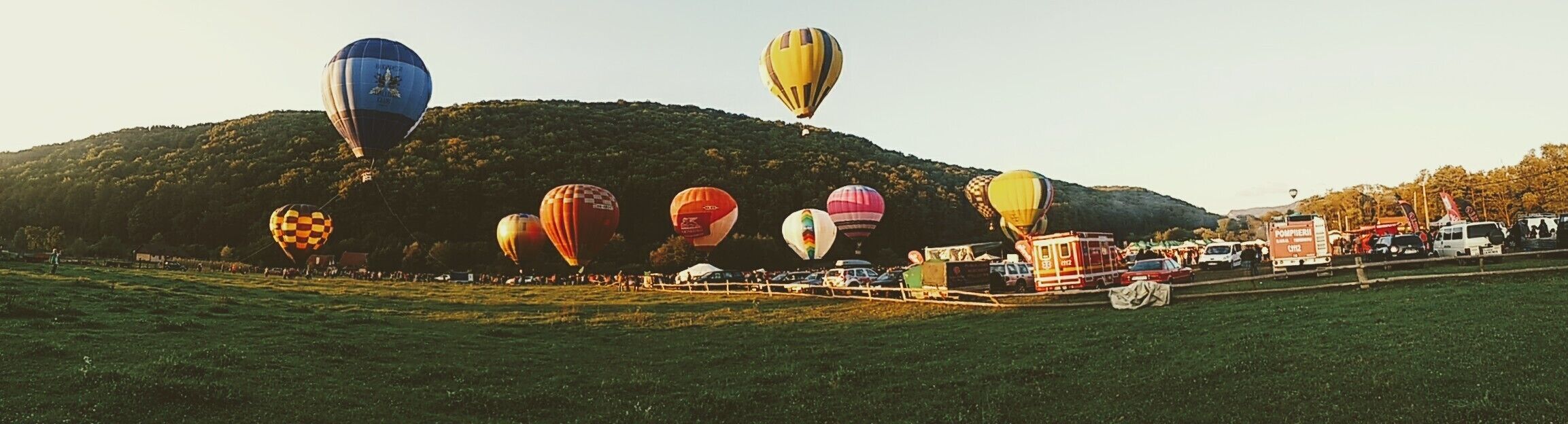 A hot air balloon festival with colorful balloons and a crowd of spectators.