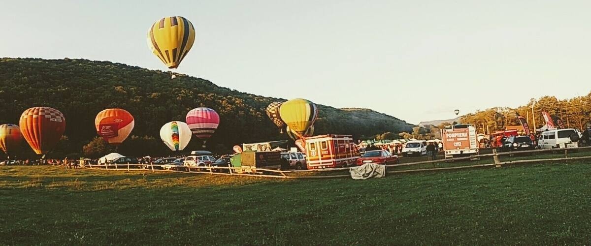 A hot air balloon festival with colorful balloons and a crowd of spectators.