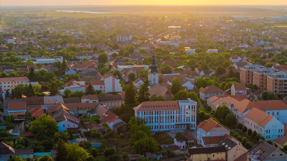 A town with a mix of residential and commercial buildings, surrounded by greenery.